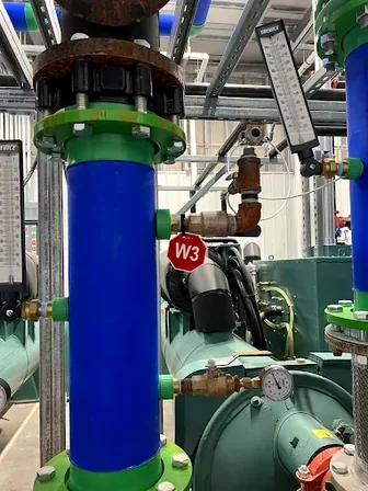Industrial piping with a W3 lockout point clearly identified, the kind of point-of-use placard 1910.147(c)(4) requires