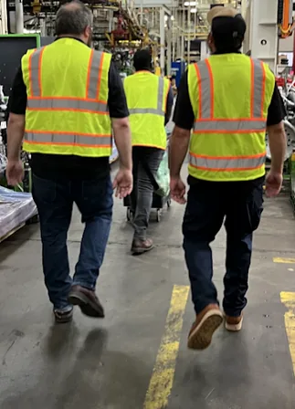 Trained safety professionals walking a manufacturing floor in high-visibility vests during an on-site LOTO gap analysis