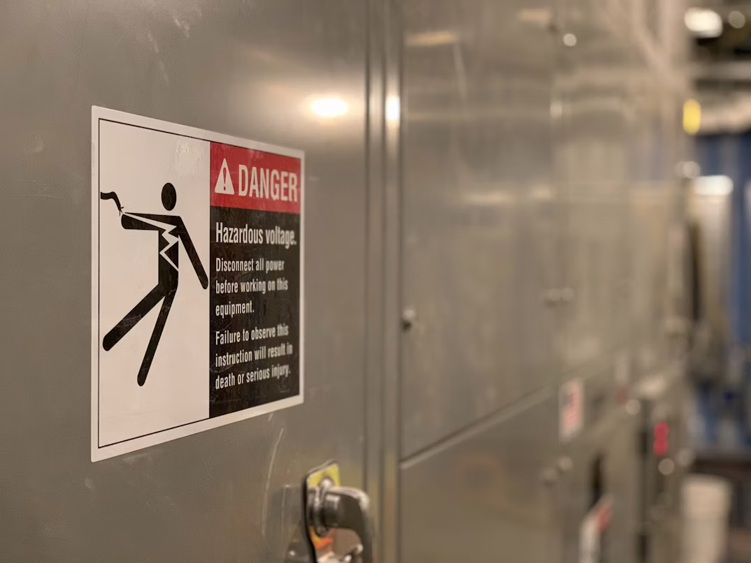 DANGER hazardous voltage LOTO placard on industrial electrical panel — machine-specific lockout tagout signage